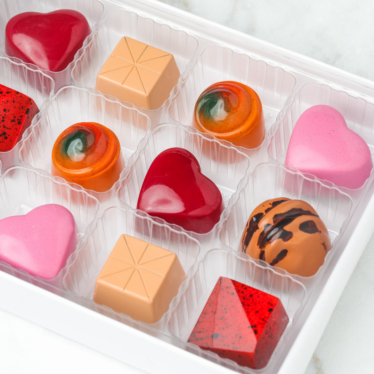 A curated box of Botolino handcrafted chocolate confections; hearts, spheres, and geometric shapes