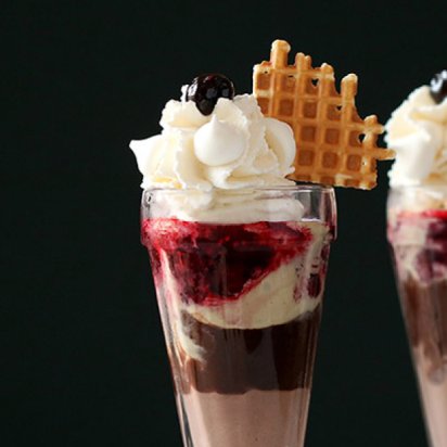 A sundae glass revealing rich layers of dark chocolate, vibrant berry compote, and creamy handcrafted gelato